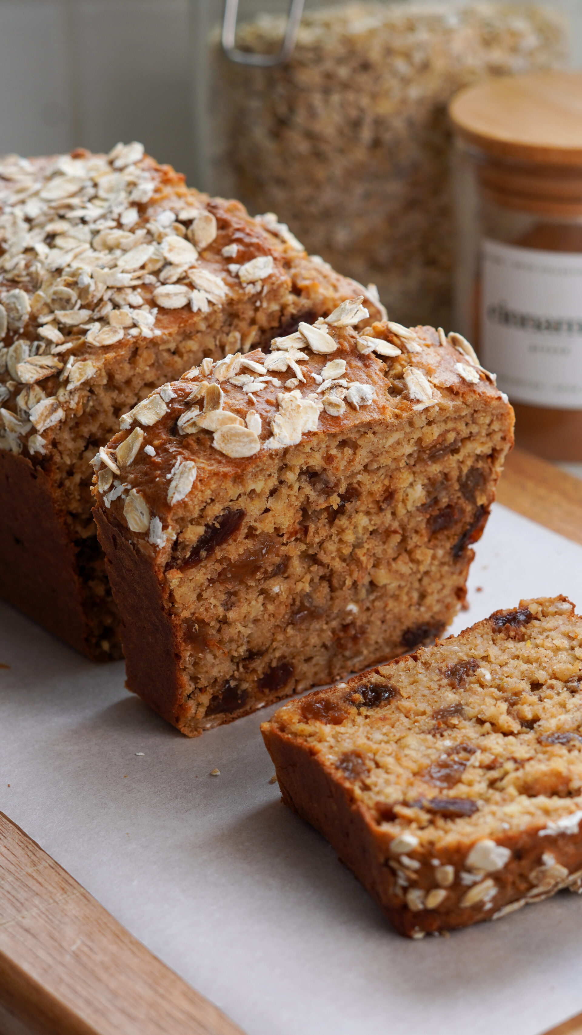Sweet cottage cheese bread with raisins, sliced on a wooden board with parchment paper and oats sprinkled on top.