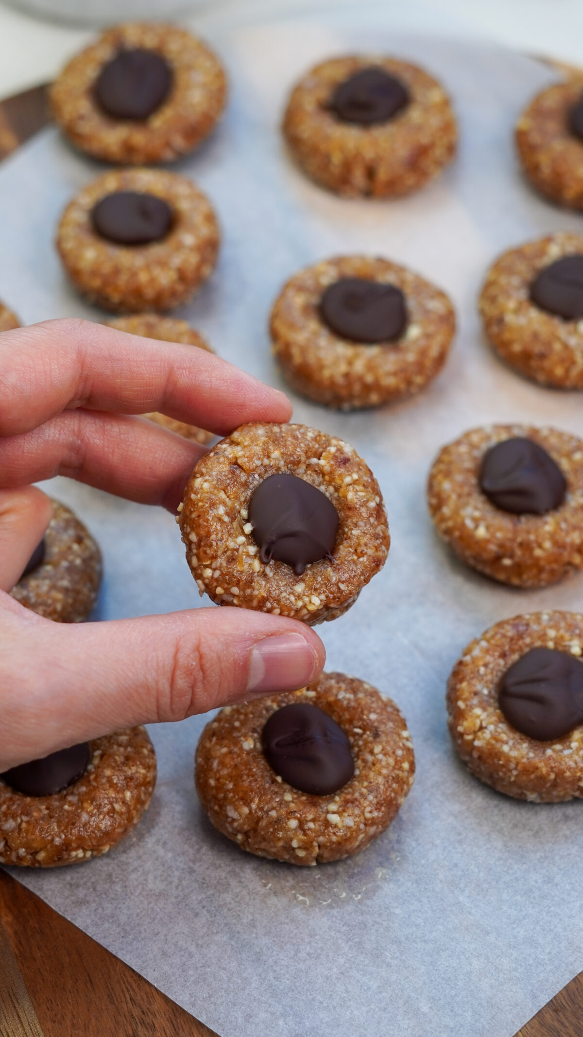 Hand holding a cashew chocolate bite with more bites on a tray in the background