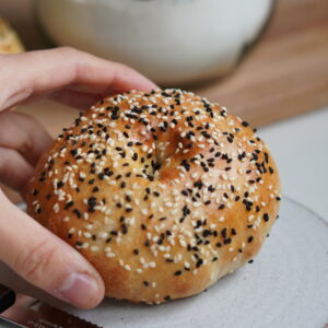 Close up of bagel on white plate and sesame seeds