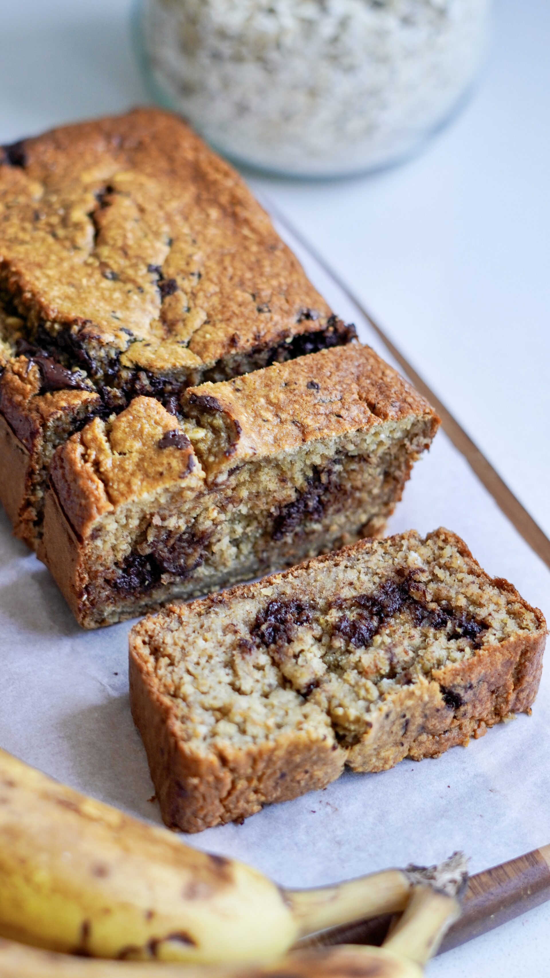 Healthy banana bread with two slices on a chopping board lined with parchment paper