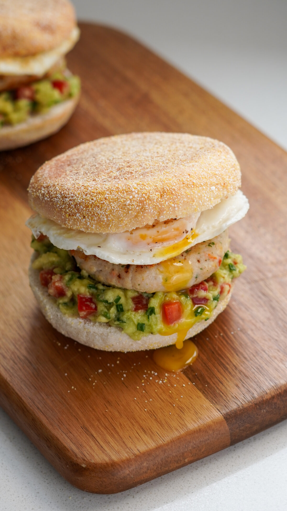 Chicken Sausage English Muffin with herby chicken patty, mashed avocado salsa, fried egg, and soft muffin – a healthy high-protein breakfast.