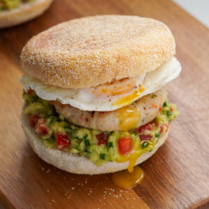 Chicken Sausage English Muffin with herby chicken patty, mashed avocado salsa, fried egg, and soft muffin – a healthy high-protein breakfast.